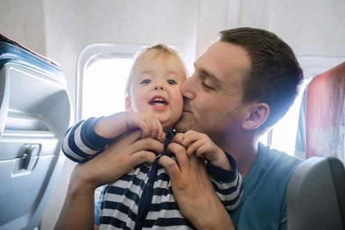 baby on a plane being kissed by his dad
