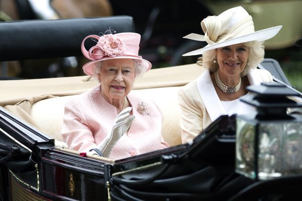 Britain’s Queen Elizabeth II waves to the crowds with Camilla, Duchess of Cornwall at right, as they arrive by carriage on the first day of the Royal Ascot horse race meeting in Ascot, England, Tuesday, June 18, 2013.