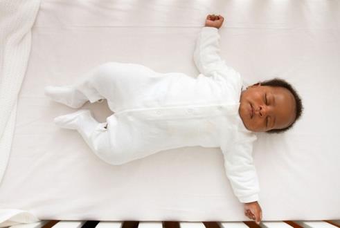 baby sleeping on their back in empty cot
