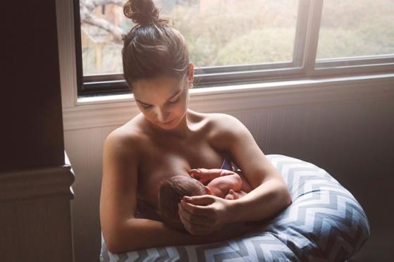 woman breastfeeding baby on nursing pillow