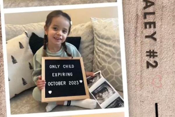 child holding up message board saying o<em></em>nly child expiring October 2023